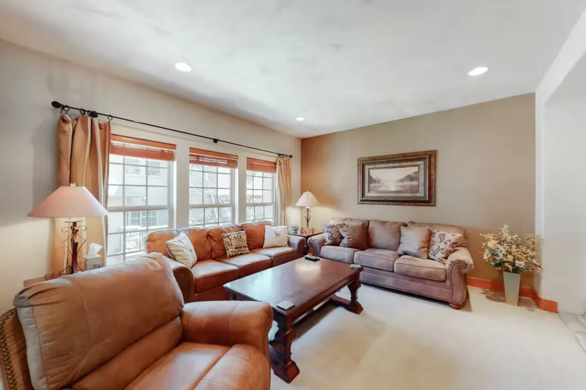 A welcoming living room with plush leather sofas, a wooden coffee table, and art adorning the walls. The setup is designed for relaxation, conversation, and movie nights, making it ideal for families or multiple groups to unwind together.
